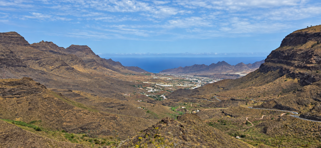 Mountain valley with a settlement and ocean beyond in Gran Canaria.